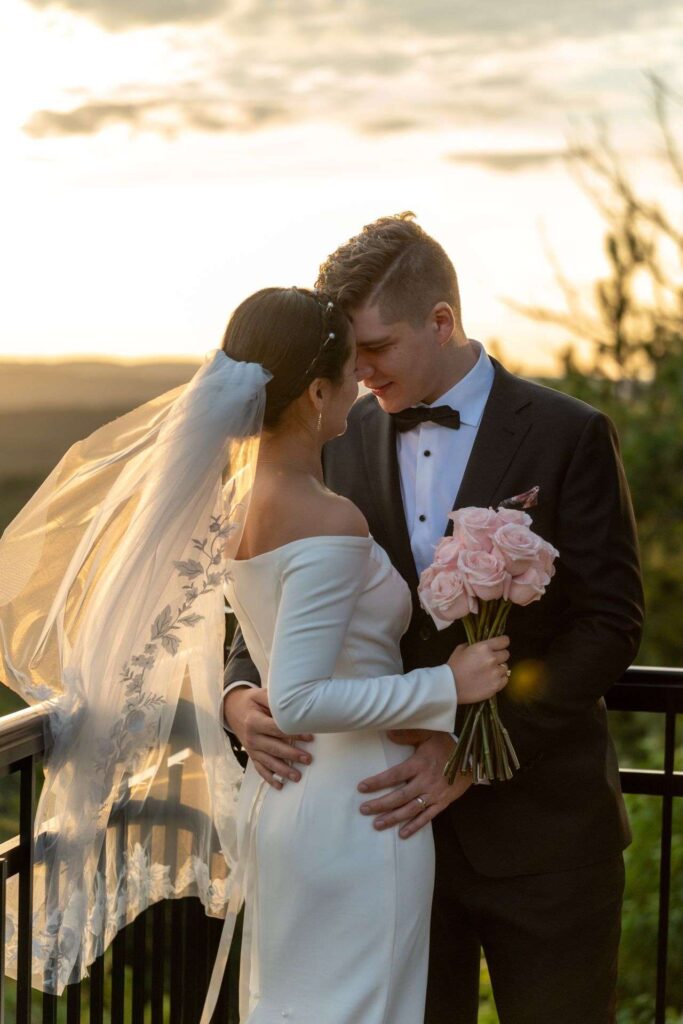 Mariés au coucher du soleil sur une terrasse avec bouquet, photographe mariage Montréal.