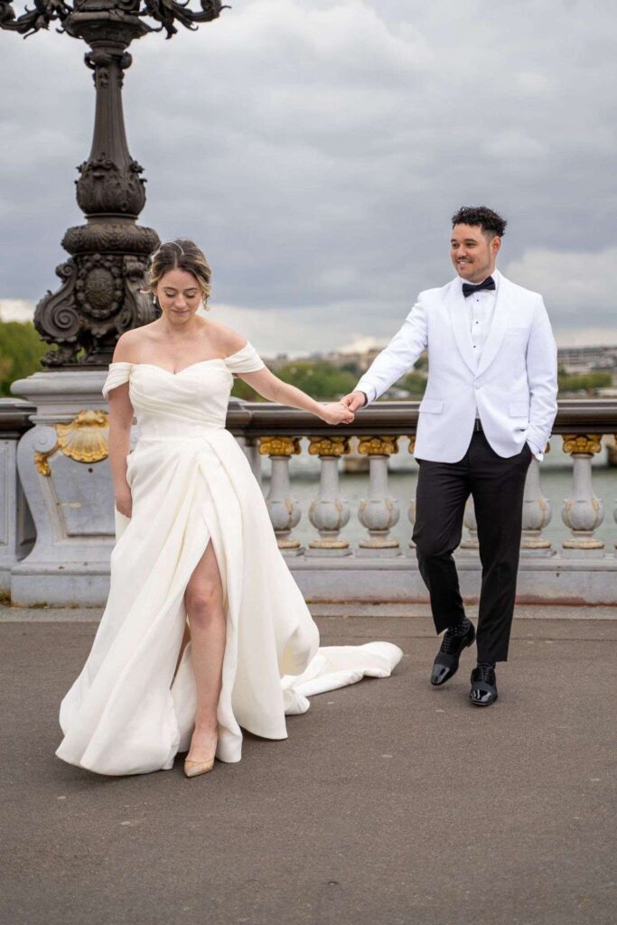 Mariés se tenant la main sur un pont parisien, séance photo de mariage à Paris — mariage à destination